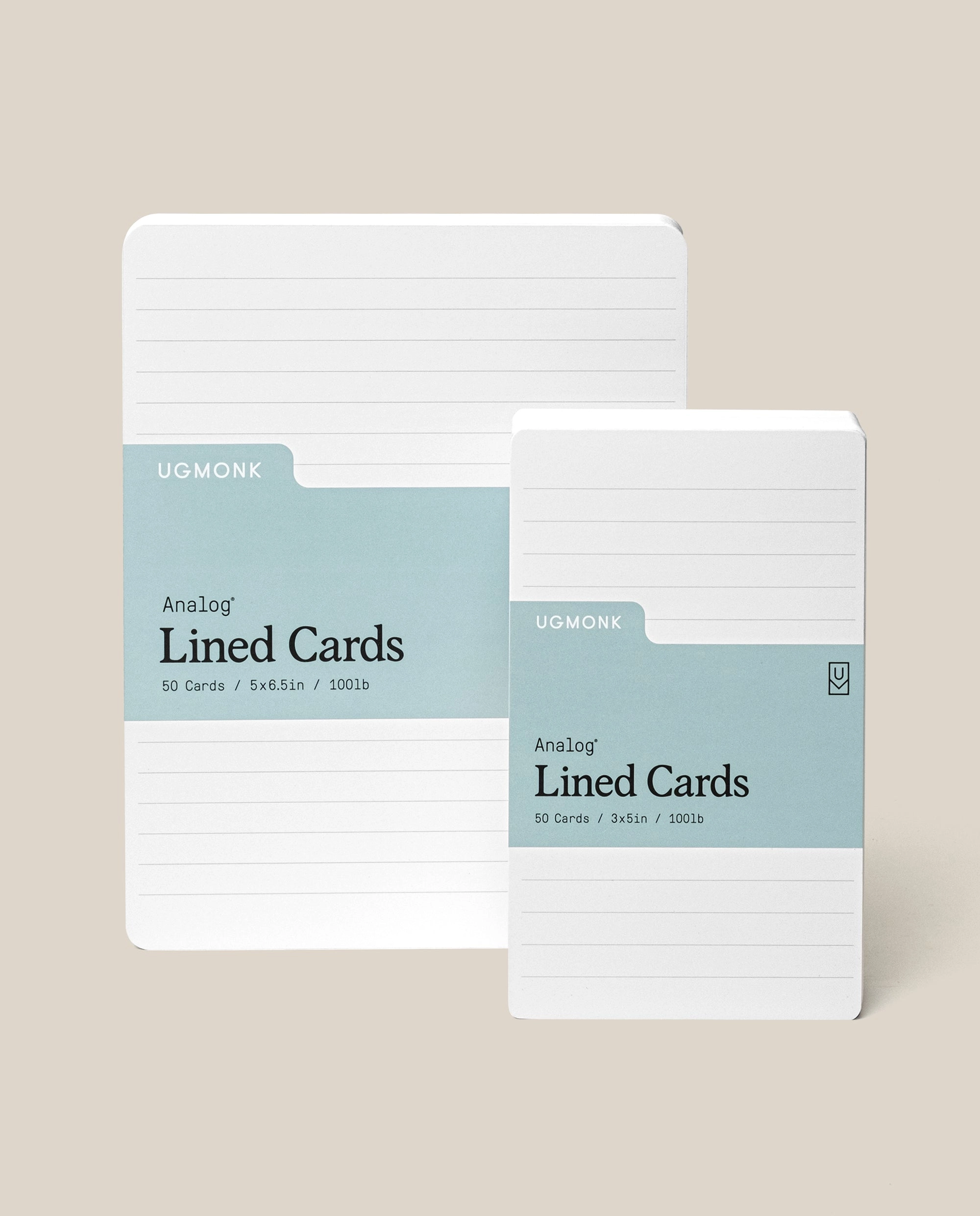 Two stacks of white lined cards with blue-green labels, branded UGMONK Analog Lined Cards. One stack is larger (5x8.5in), and the other is smaller (3x5in), both with rounded corners on a beige background.