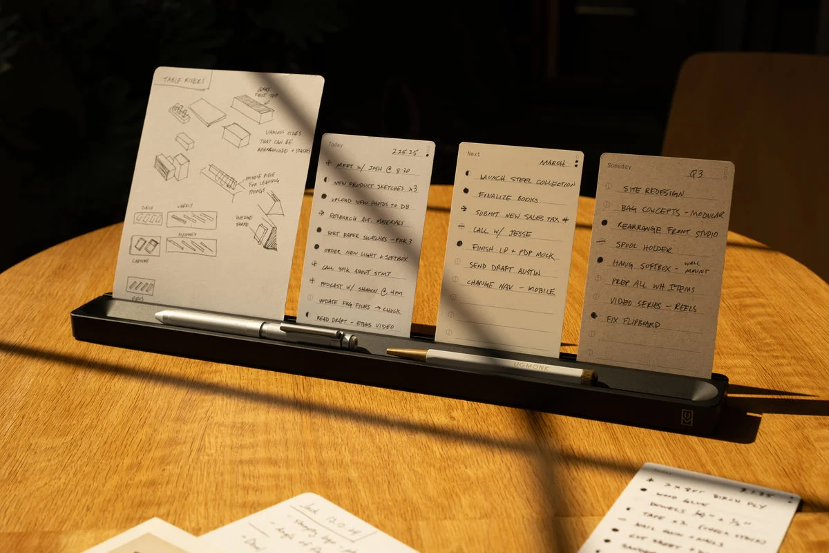 Handwritten Analog cards standing in a black aluminum card bar on a sunlit desk